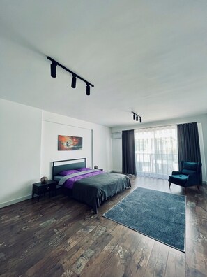 Quarto moderno com cama, uma cadeira, um tapete e um quadro na parede.
