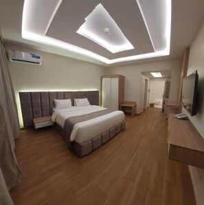 A modern hotel room with a large bed, a desk, a wardrobe, and a television. - Goldn Almdyaf (Abha)