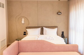 A neatly made bed with white linens, a bedside table with a phone, and a wall-mounted light fixture. - Si Hotel Sh.p.k (Tirana)