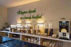 A breakfast bar with a coffee machine, various breakfast items, and a wall sign stating 'All happiness depends on a lovingly breakfast.' - Si Hotel Sh.p.k (Tirana)