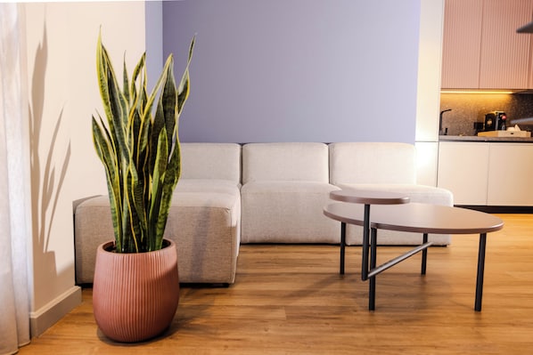 A modern living room with a sofa, a coffee table, and a potted plant. - Si Hotel Sh.p.k (Tirana)