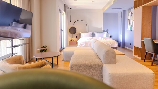 A modern hotel room with a large bed, a TV, a sofa, a small table, and a desk. - Si Hotel Sh.p.k (Tirana)
