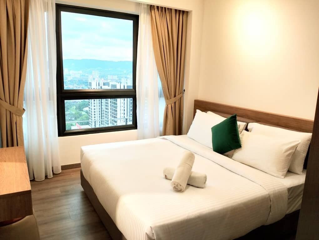 A hotel room with a bed, a view of a cityscape through a window, and a wooden headboard.