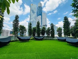 A rooftop garden with artificial grass, black seating, and tall buildings in the background. - Agile Platinum Suite Trx Kl (Kuala Lumpur)