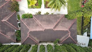 Eine Vogelperspektive auf ein Wohngebiet mit geometrischen Dachmustern, grüner Bepflanzung und einer weißen Mauer.