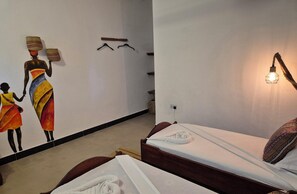 Une chambre avec deux lits, une fresque murale, un luminaire suspendu et une prise de courant.