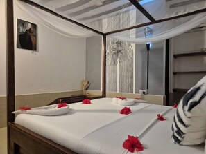 Une chambre d’hôtel avec un lit, un miroir, un tableau et une fenêtre avec des rideaux.