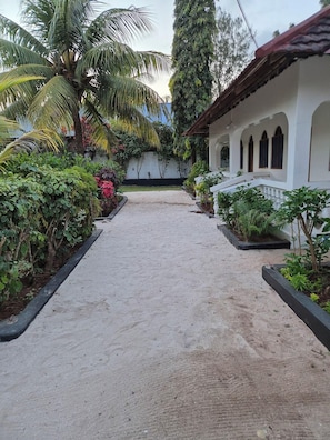 A pathway leading to a building with a white facade and arched windows. - Ellavita Cottages Zanzibar (Nungwi)