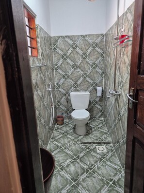 Et badeværelse med toilet, bidet og bruseområde.