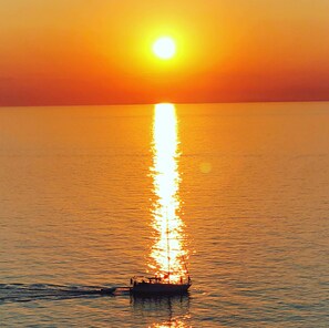 Ein Boot mit Personen, das sich in der Sonne auf dem Wasser spiegelt.
