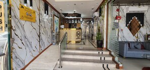 Un vestíbulo de hotel con paredes de mármol, un mostrador de recepción, una escalera y un área de estar.
