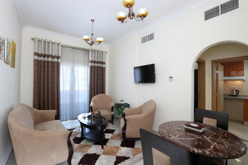 Una sala de estar con un sofá, sillones, una mesa de centro, un televisor y una mesa de comedor.