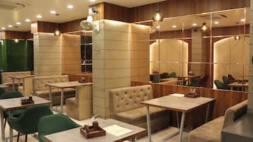 A modern restaurant interior with booths, tables, and a large mirror wall.