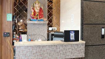 A reception desk with a statue, a check-in kiosk, and a QR code for digital check-in.