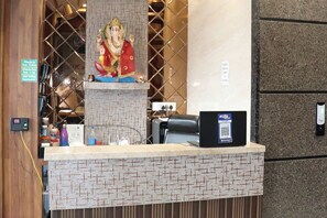 Ein Empfangsschalter mit einer Statue, ein Check-in-Terminal und ein QR-Code für die digitale Anmeldung.