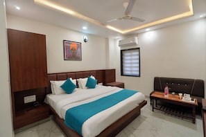 A hotel room with a bed, nightstand, and a seating area with a table. - Hotel Samrat Ajmer (Ajmer)