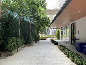 A covered walkway with planters and trees, leading to a building with glass doors. - 35 Bow Hotel & Complex (Bangkok)