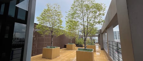 A corridor with wooden flooring, potted plants, and a wooden fence.