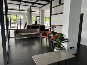 Um hall moderno com sofá, cadeiras, uma mesa e plantas em vasos.