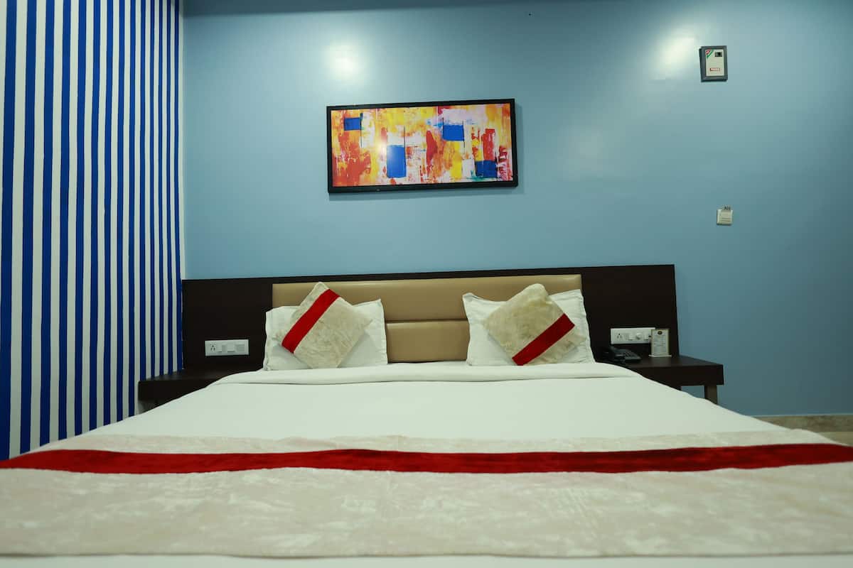 A hotel room with a bed, a nightstand, a wall-mounted painting, and a striped curtain.
