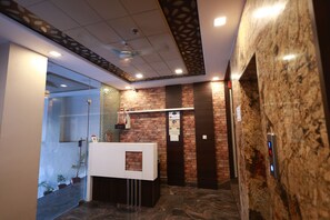 Un espace d’accueil au design moderne, comprenant un comptoir d’accueil, un mur en verre et un plafond orné d’un motif décoratif.