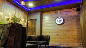 Una habitación con paneles de madera, un letrero de neón circular y dos sillones de cuero negro.