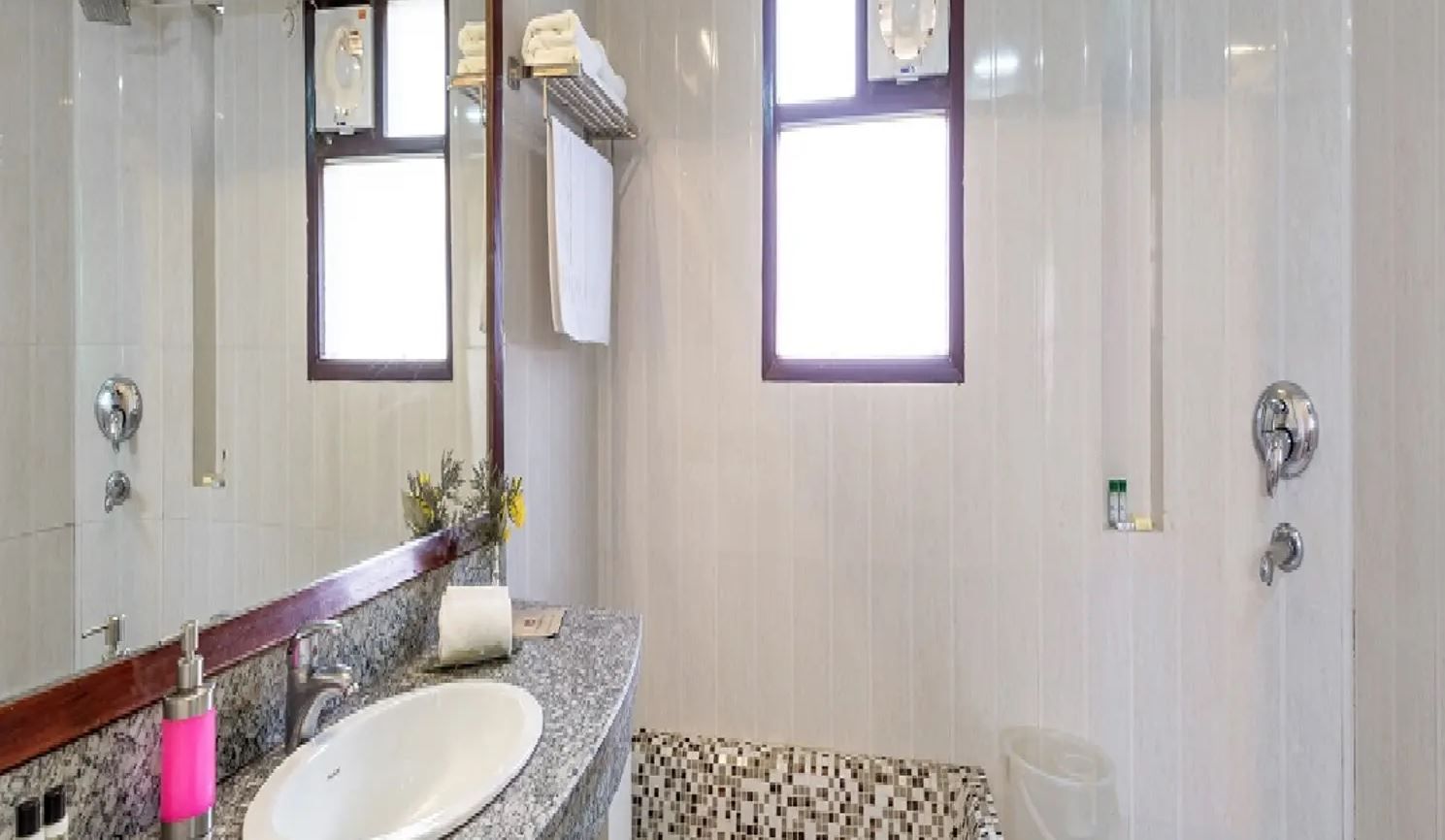 A bathroom with a marble sink, a mirror, a towel rack, and a shower area.