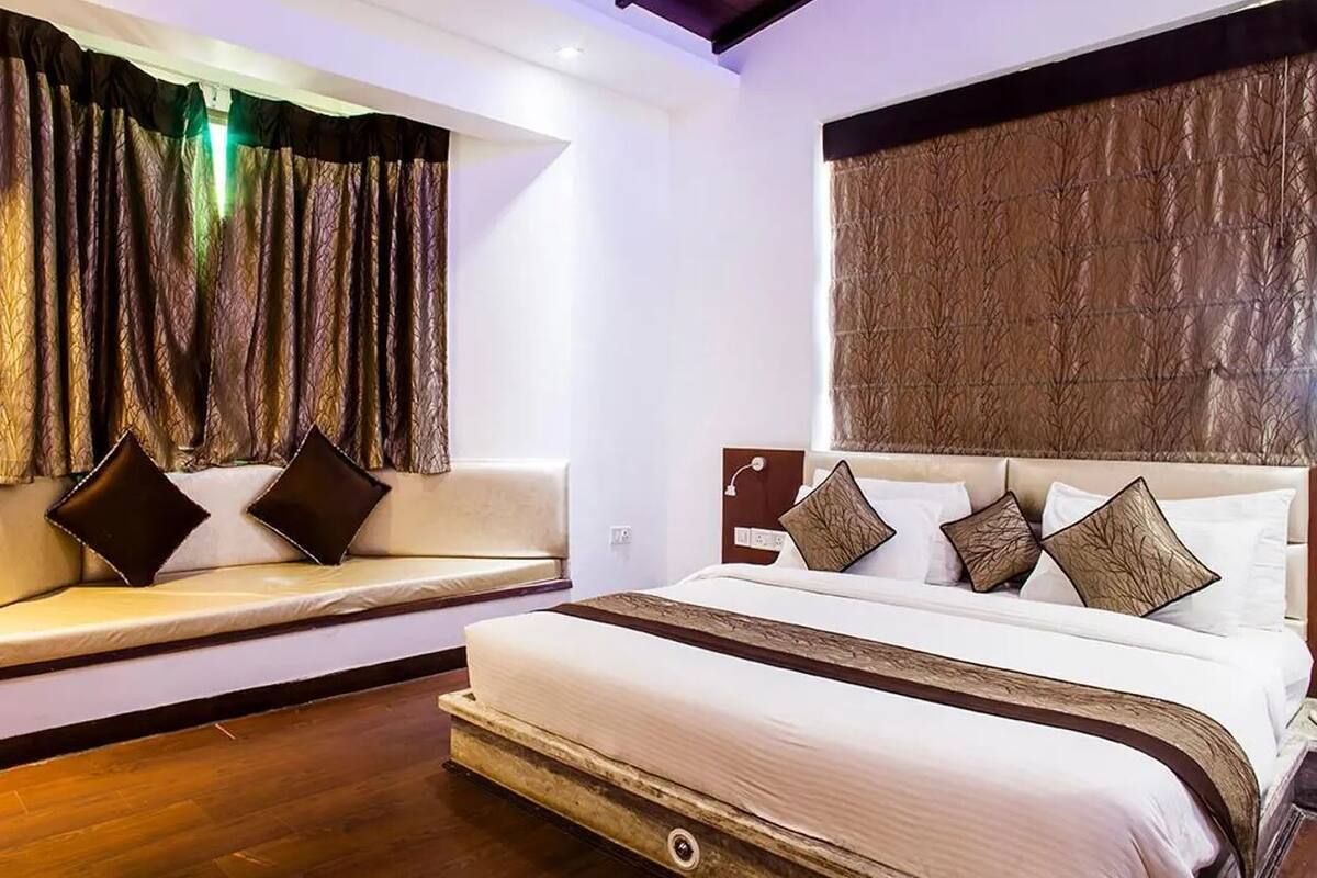 Una habitación de hotel con cama, sofá y ventana con cortinas.