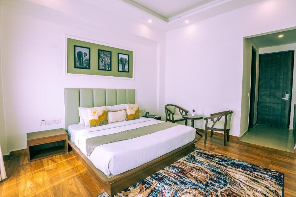 Un dormitorio con cama, mesita de noche, silla y una puerta que da a otra habitación.