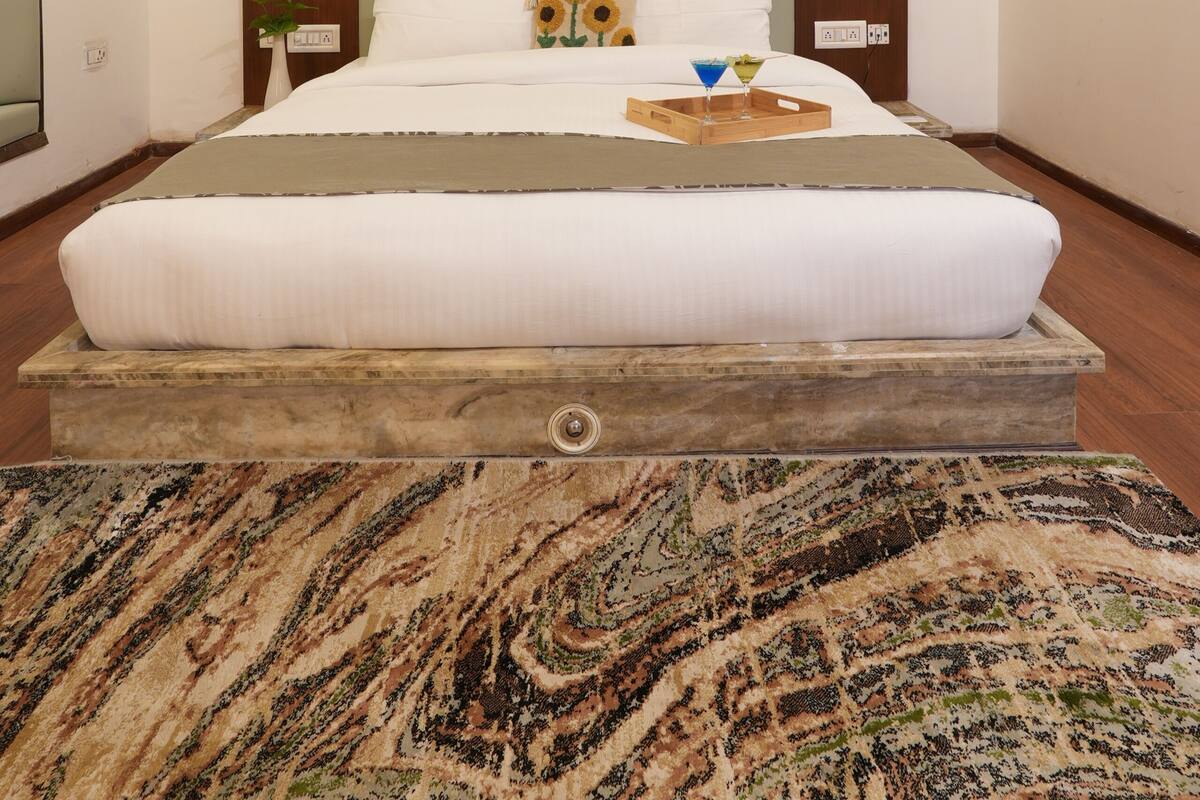Un dormitorio con una cama grande, cabecera de madera, ventana con persianas, mesita de noche con lámpara y aire acondicionado instalado en la pared.