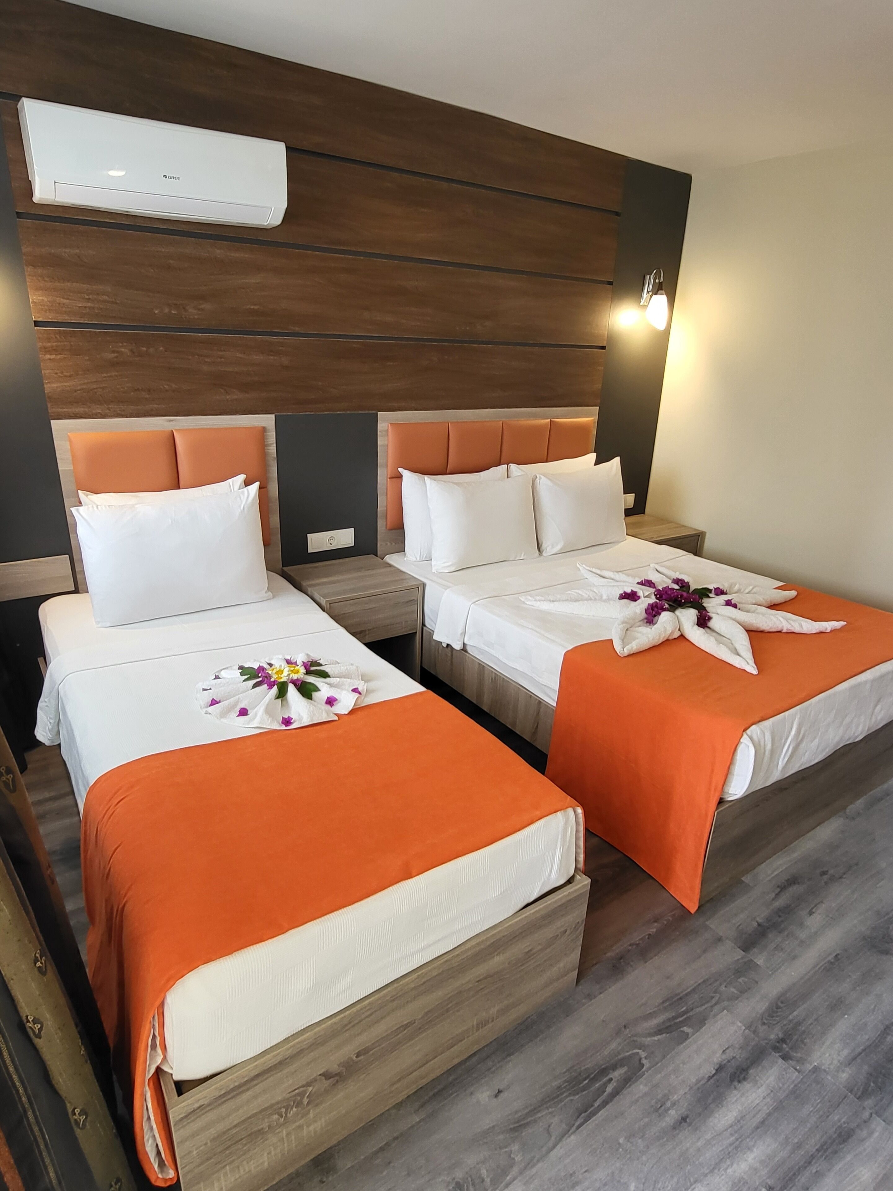 A hotel room with two beds, an air conditioning unit, wooden headboard, and a nightstand.