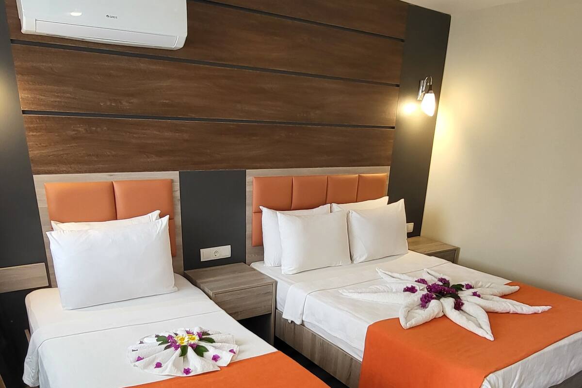 A hotel room with two beds, an air conditioning unit, wooden headboard, and a nightstand.
