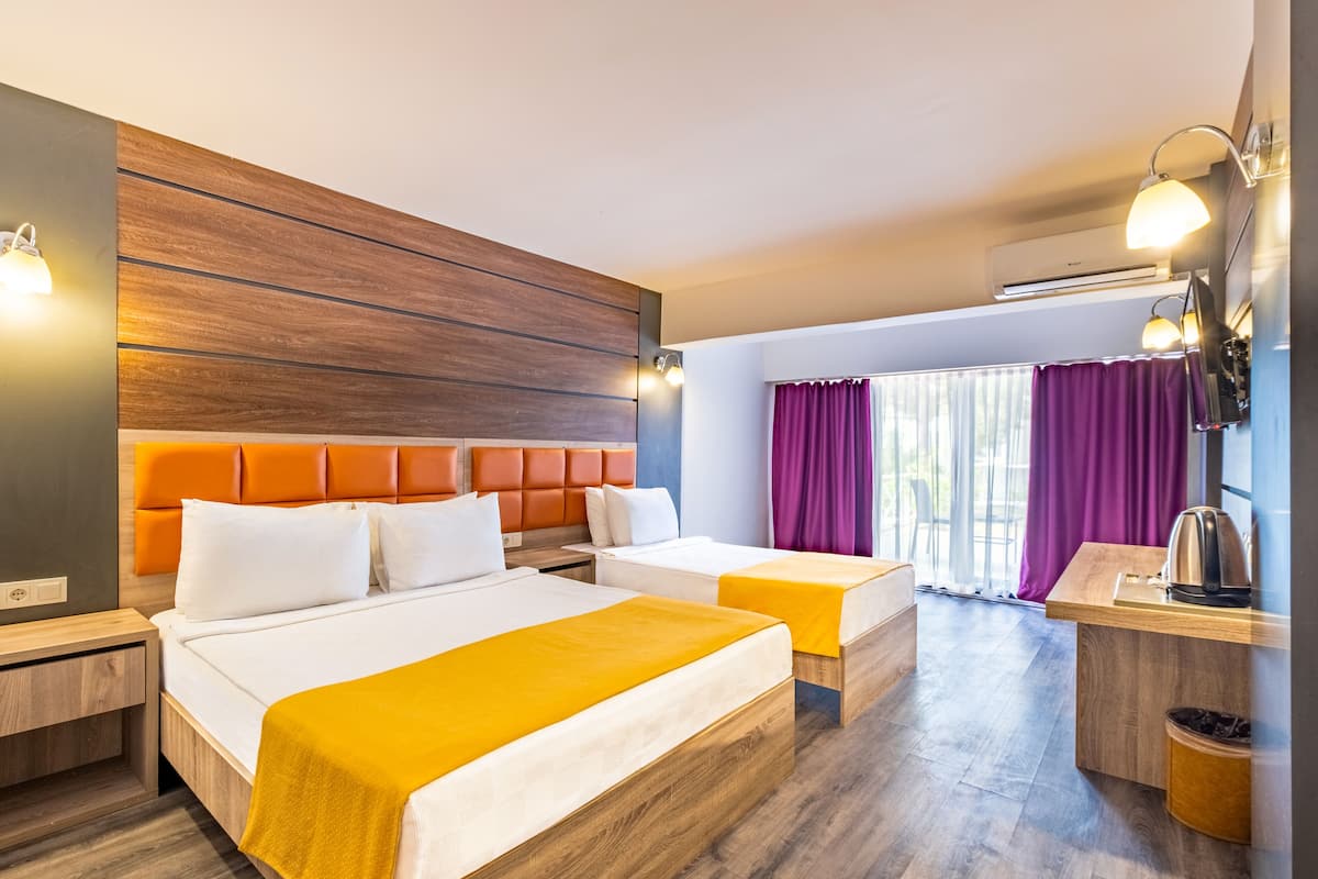Moderni hotellihuone, jossa on kaksi sänkyä, puinen pääty, pieni työpöytä ja ikkuna, jossa on violetit verhot.