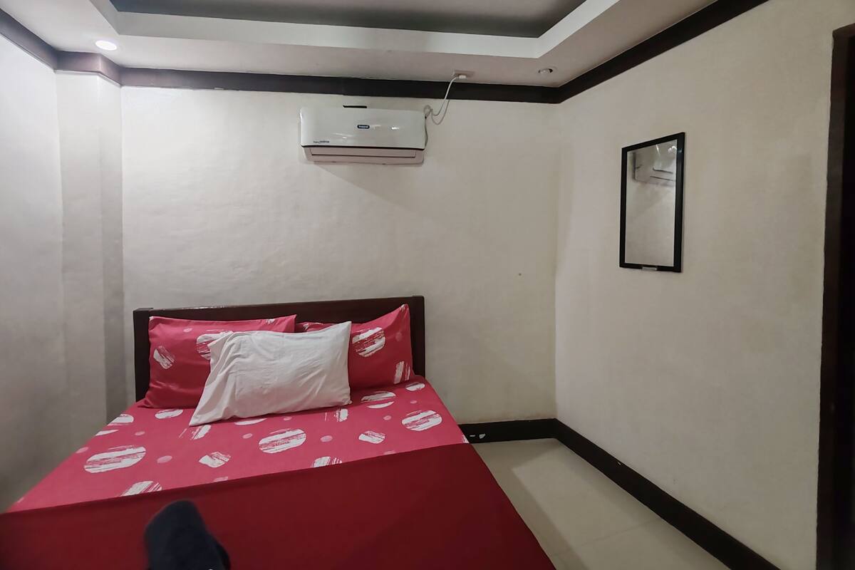 Ein Schlafzimmer mit einem Bett, einer Klimaanlage und einem gerahmten Bild an der Wand.