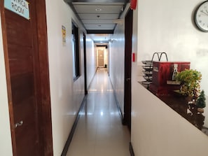 Un pasillo de hotel con un cartel que indica 'Habitación Crítica', un reloj y una canasta roja con la etiqueta 'Caja de Propinas'.