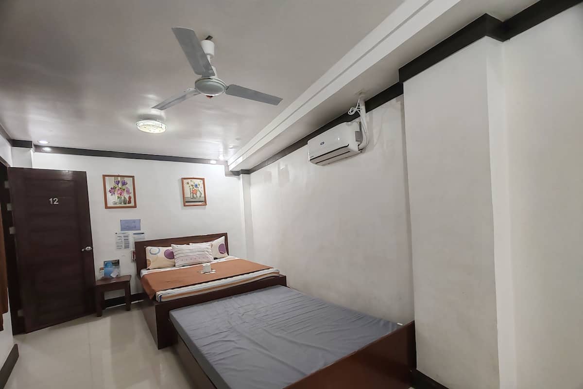 Ein Schlafzimmer mit einem Bett, einem Deckenventilator, einer Klimaanlage und einer Tür mit der Nummer 12.