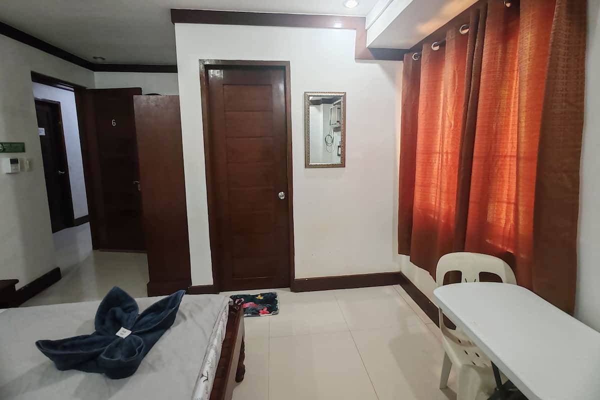 Ein Hotelzimmer mit Bett, Schreibtisch, Stuhl, Tür und Spiegel.