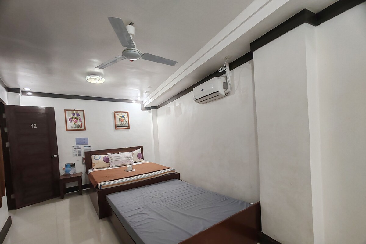 Un dormitorio con cama, ventilador de techo, aire acondicionado y una puerta marcada con el número 12.