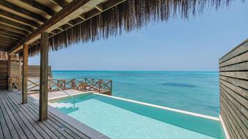 A wooden deck with a pool overlooking turquoise waters.
