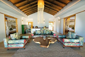 A spacious living area with a large sofa set, a coffee table, and a high ceiling with wooden beams. - Bawe Island Resort (Bawe Island)