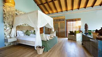 Un dormitorio con cama a dosel, una zona de estar con sofá, techo de madera y una lámpara colgante decorativa de gran tamaño.