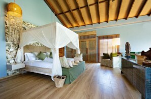 A bedroom with a canopy bed, a sitting area with a sofa, a wooden ceiling, and a large decorative hanging light. - Bawe Island Resort (Bawe Island)