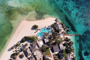 An aerial view of a resort with a swimming pool, beach, and thatched-roof structures. - Bawe Island Resort (Bawe Island)