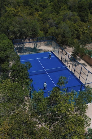 An outdoor tennis court surrounded by dense trees. - Bawe Island Resort (Bawe Island)