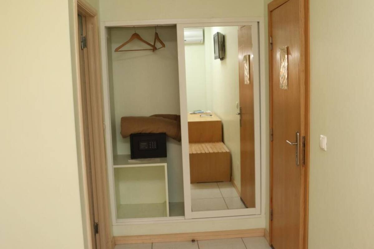 A bedroom with a wardrobe, a bed, a bedside table, and a TV.
