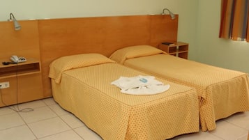 A room with two beds, a bedside table, a lamp, a phone, and a curtain.