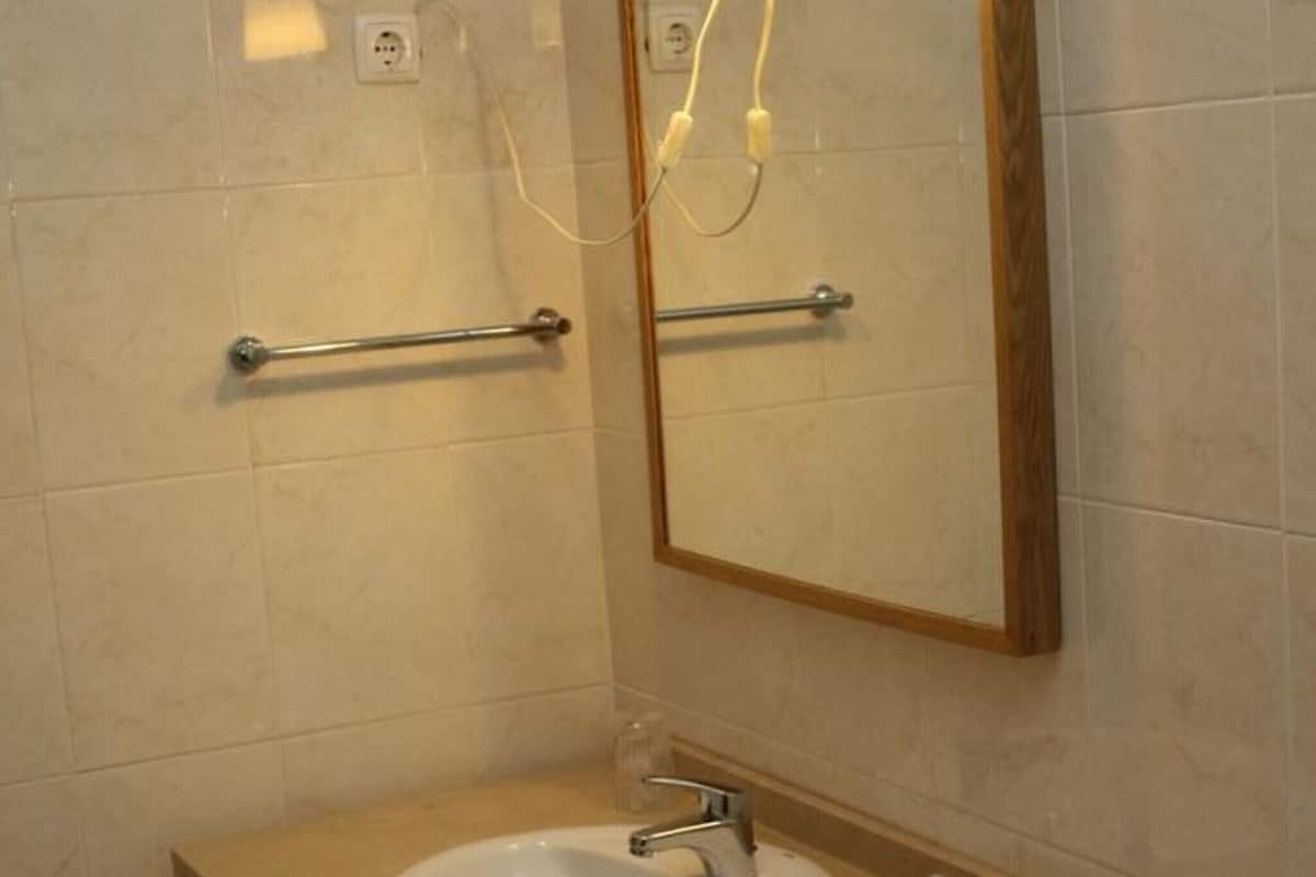 Un baño con lavamanos, espejo, toallero e iluminación empotrada.