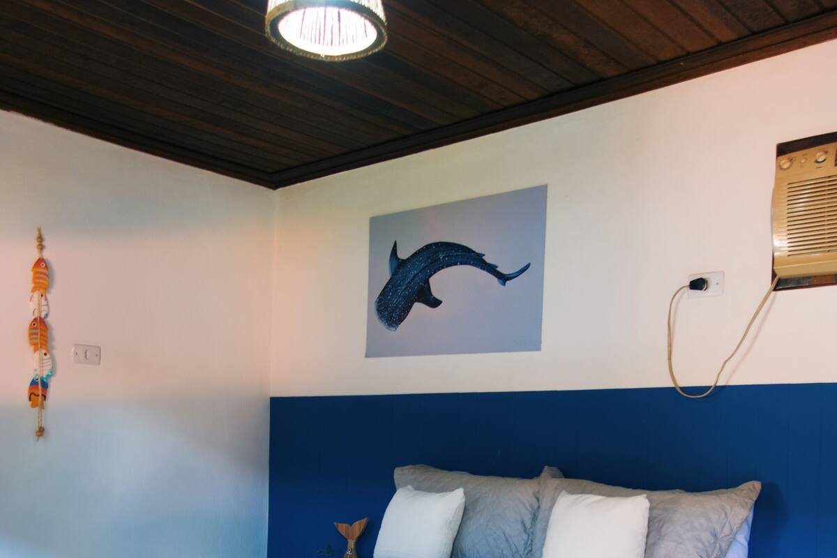 A bedroom with a bed, a chandelier, a wall painting, and a wall-mounted heater.