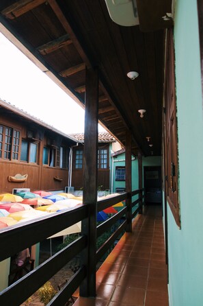 A covered corridor with wooden beams, a tiled floor, and a railing. - Pouso De Icaro (Paraty)