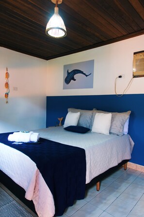 A bedroom with a bed, a chandelier, a wall painting, and a wall-mounted heater. - Pouso De Icaro (Paraty)